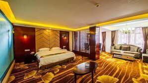 Una habitación de hotel con cama, sofá, una mesita de café y un panel decorativo en la pared.