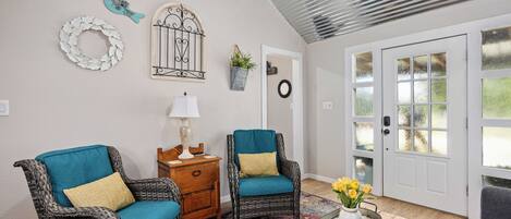 Una habitación acogedora con muebles de mimbre, un tapete estampado y una puerta con paneles de vidrio esmerilado.