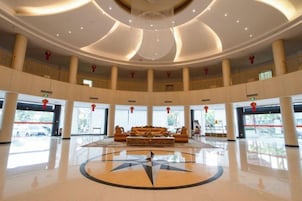 A spacious lobby with a central seating area, multiple levels with balconies, and a large chandelier.
