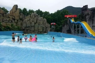 A water park with a large pool, slides, and rock formations.