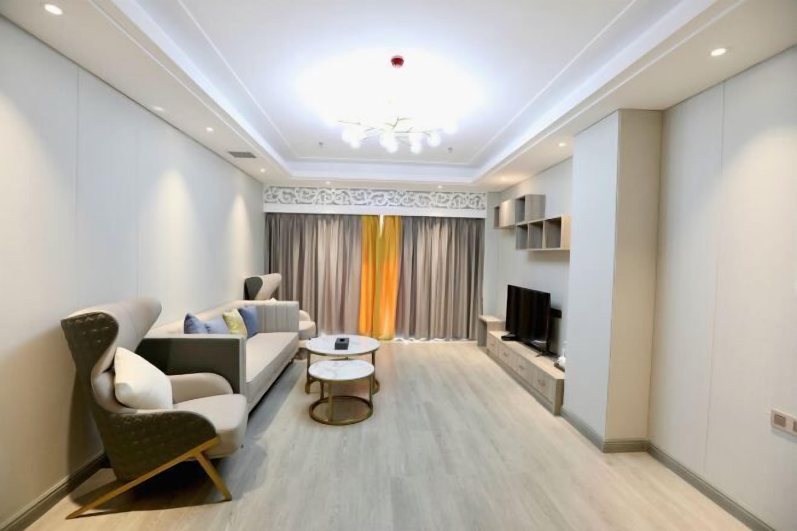 A modern living room with a sofa, armchair, coffee table, and TV.