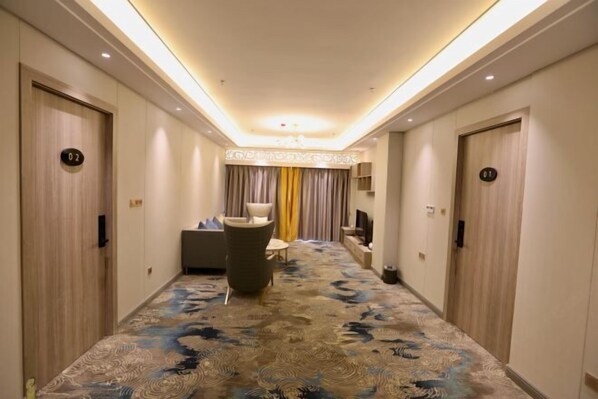 A hotel hallway with a patterned carpet, a seating area with a sofa and chairs, and doors numbered 01 and 02.