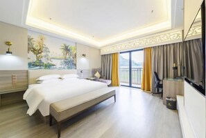 Una habitación de hotel moderna con una cama grande, mesitas de noche, un televisor y un balcón con cortinas.