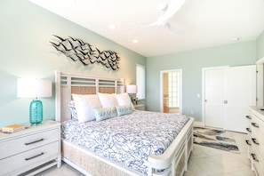 Quarto com cama, mesas de cabeceira, uma obra de arte na parede e uma porta.