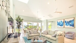 Un salon spacieux avec une grande fenêtre, un ventilateur de plafond et une table basse.
