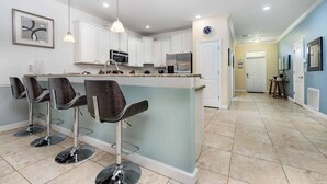 A modern kitchen with white cabinets, a central island with bar stools, and a clock on the wall. - Upscale Family Home w/ Custom Arcade, Theatre (Davenport)