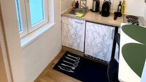 Een compacte keuken met witte marmeren kastjes, een spoelbak, een waterkoker en een klein aanrecht.