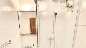 Een badkamer met een douchecabine, een wastafel en een toilet.