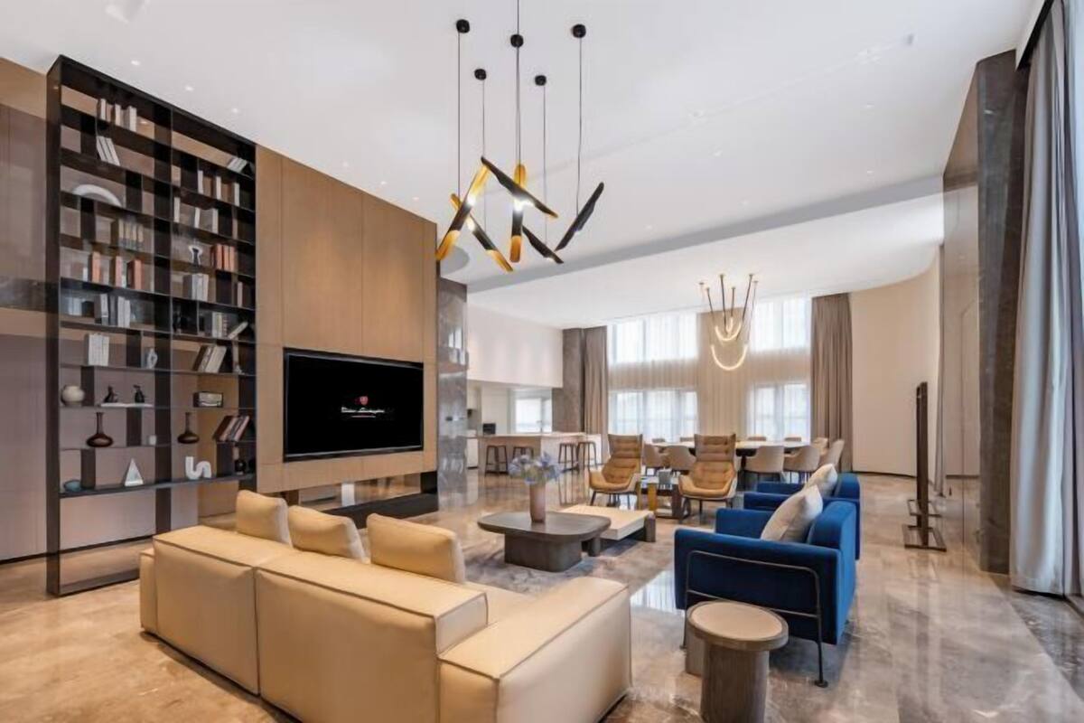 Een moderne woonkamer met een bank, fauteuils, een televisie en een boekenkast.