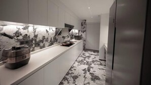 A modern kitchen with white cabinets, a marble backsplash, and a stainless steel appliance on the counter.