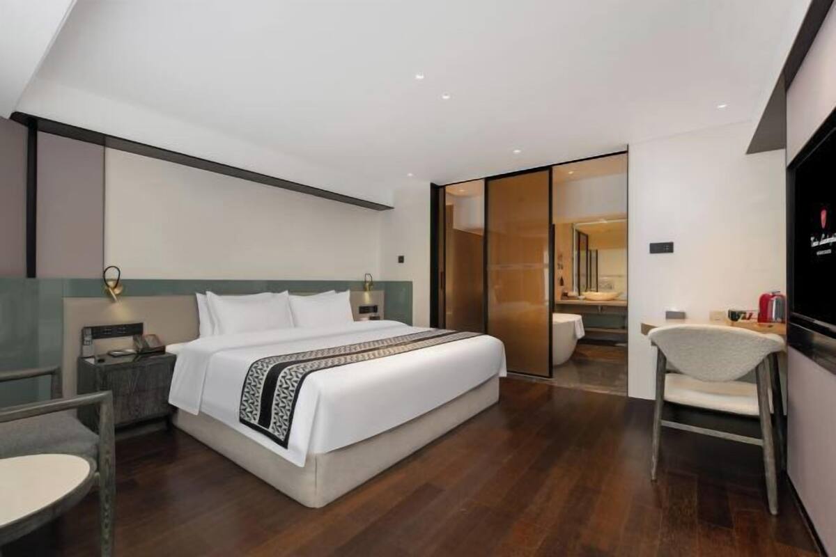 Een moderne hotelkamer met een groot bed, een bureau, een stoel en een televisie.