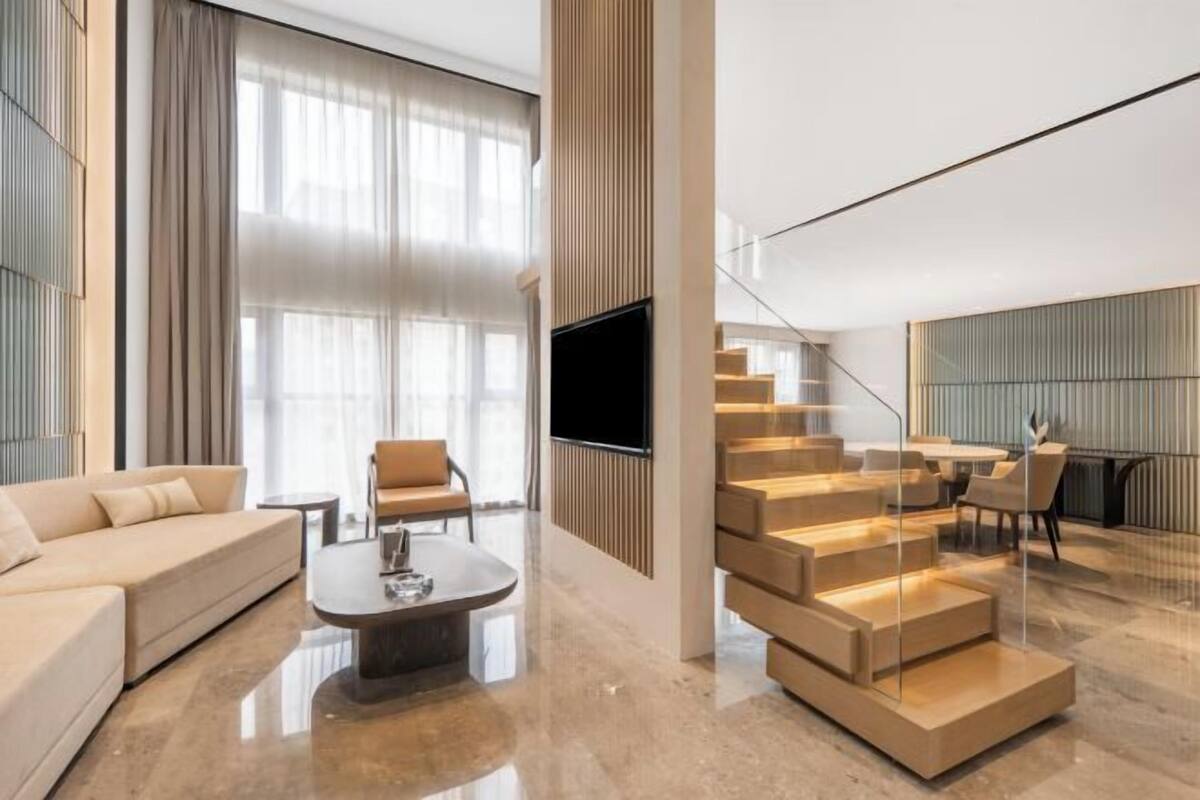 Een moderne woonkamer met een bank, salontafel en een trap met ingebouwde verlichting.