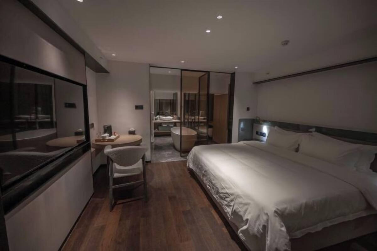 Een moderne hotelkamer met een groot bed, een bureau met stoel, een ronde tafel en een apart badgedeelte.