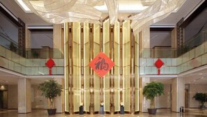 A spacious lobby with a modern design, featuring a central decorative element and potted plants.