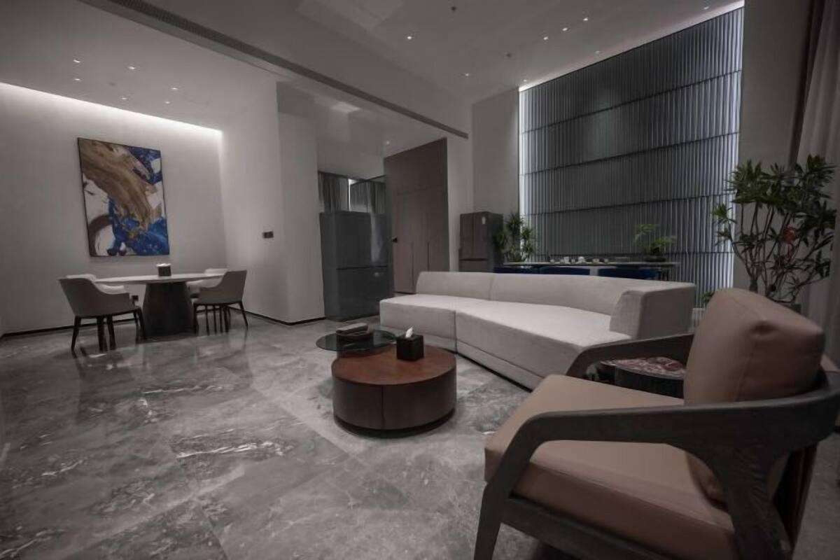 Een moderne woonkamer met een bank, fauteuil, salontafel en een eetgedeelte met stoelen en een tafel.