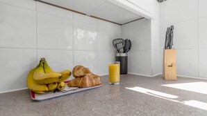 Eine Küchenarbeitsplatte mit Bananen, Croissants und einem Glas Orangensaft.