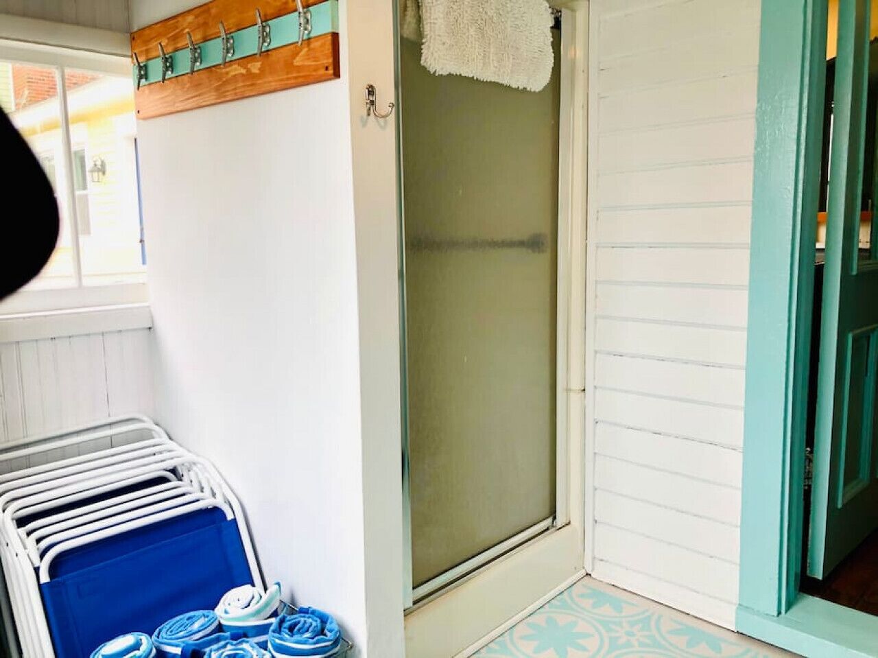 A bathroom with a glass shower door, a towel rack, and a blue towel rack with folded towels.
