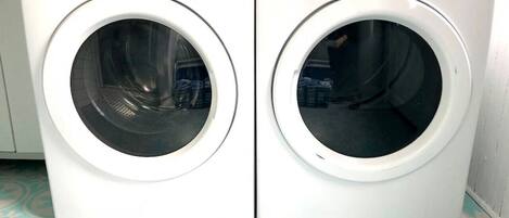 Two white front-loading washing machines with control panels, placed on a patterned floor.