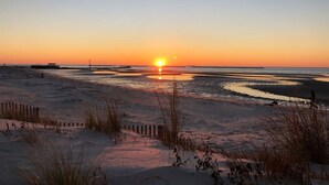 Une plage au coucher du soleil, avec une jetée en arrière-plan.