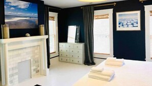 Une chambre d’hôtel avec une cheminée, un lit avec des serviettes, une commode et des œuvres d’art accrochées aux murs.
