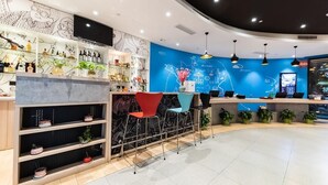 Una zona de bar con estantes llenos de botellas, una barra y taburetes.