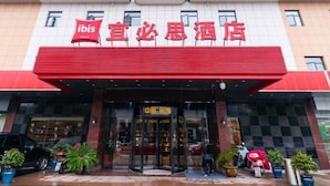 Un hotel con fachada roja y blanca, entrada de vidrio y un cartel que indica que es un hotel ibis.