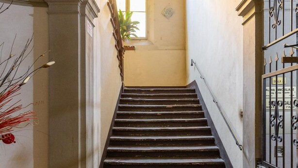 A staircase with a wrought iron railing, a decorative plant, and a window at the top. - Montegrappa Apartment by Wonderful Italy (Bologna)