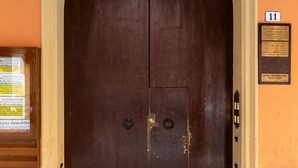A large, dark wooden door with a beige archway, a small plaque on the wall to the right, and a sign on the left. - Montegrappa Apartment by Wonderful Italy (Bologna)