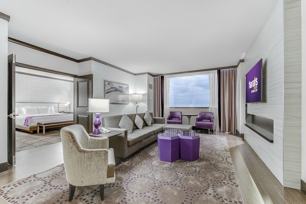 A modern hotel room with a bed, seating area, and a TV.