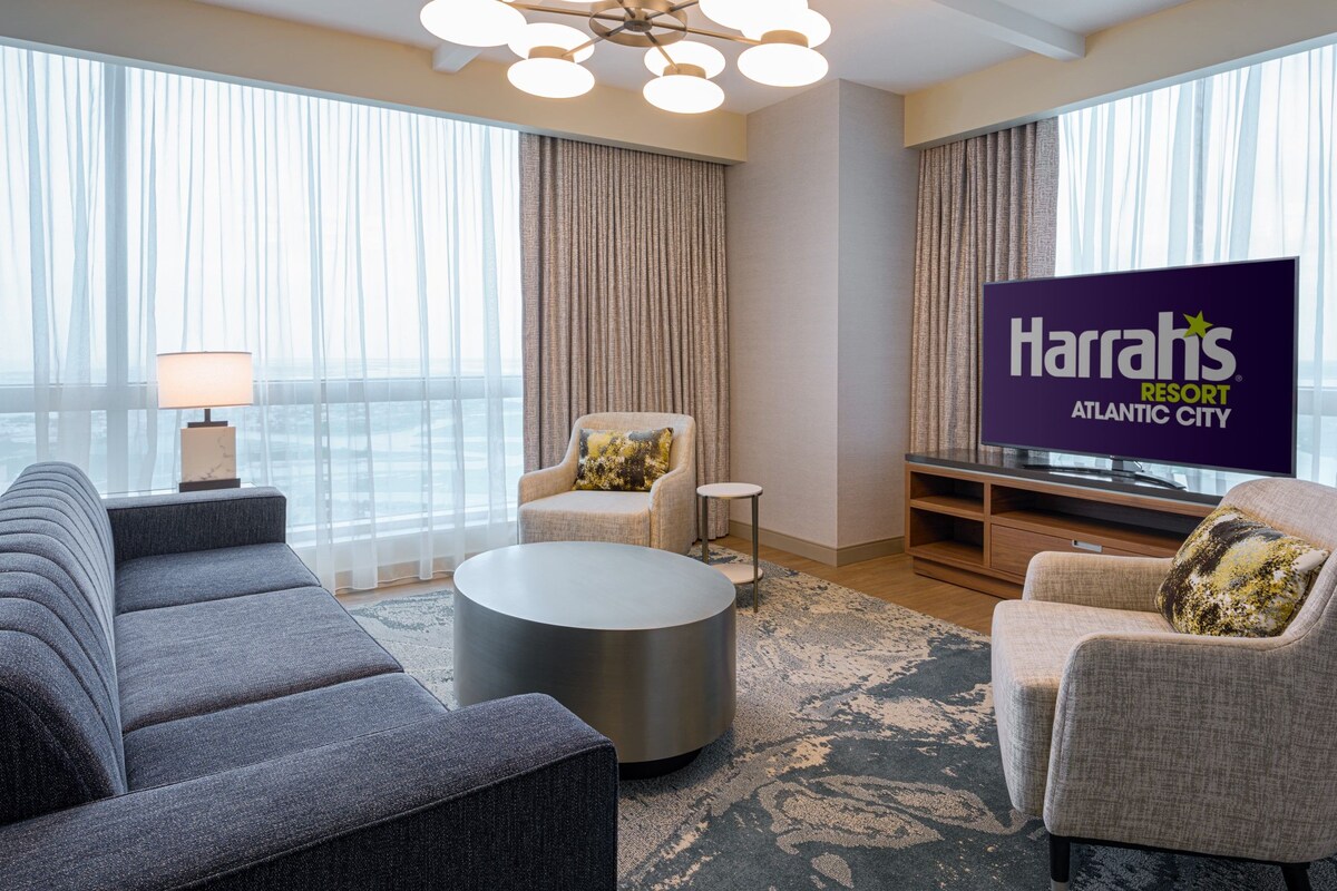 Una habitación de hotel moderna con una televisión de pantalla plana grande, un sofá, una silla y una mesa de centro.