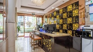 A hotel reception area with a counter, chairs, and a decorative wall. - Yi Feng Bussiness Hotel (Anning)