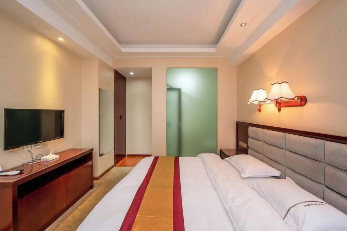 Una habitación de hotel con una cama, televisión, escritorio y lámpara.