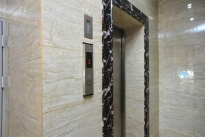 An elevator with a digital display and a marble wall. - Yi Feng Bussiness Hotel (Anning)