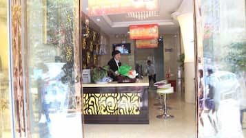 A reception area with a counter, a television screen, and a person seated behind it.