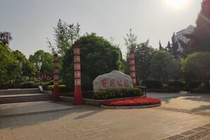 A landscaped area with a stone monument, red lanterns, and a circular flower bed. - Yi Feng Bussiness Hotel (Anning)