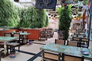 A restaurant with indoor seating, a counter, and hanging plants. - Yi Feng Bussiness Hotel (Anning)