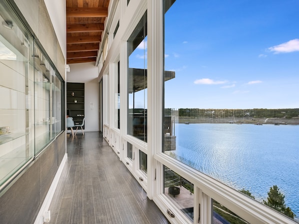 A modern balcony with large windows overlooking a body of water.