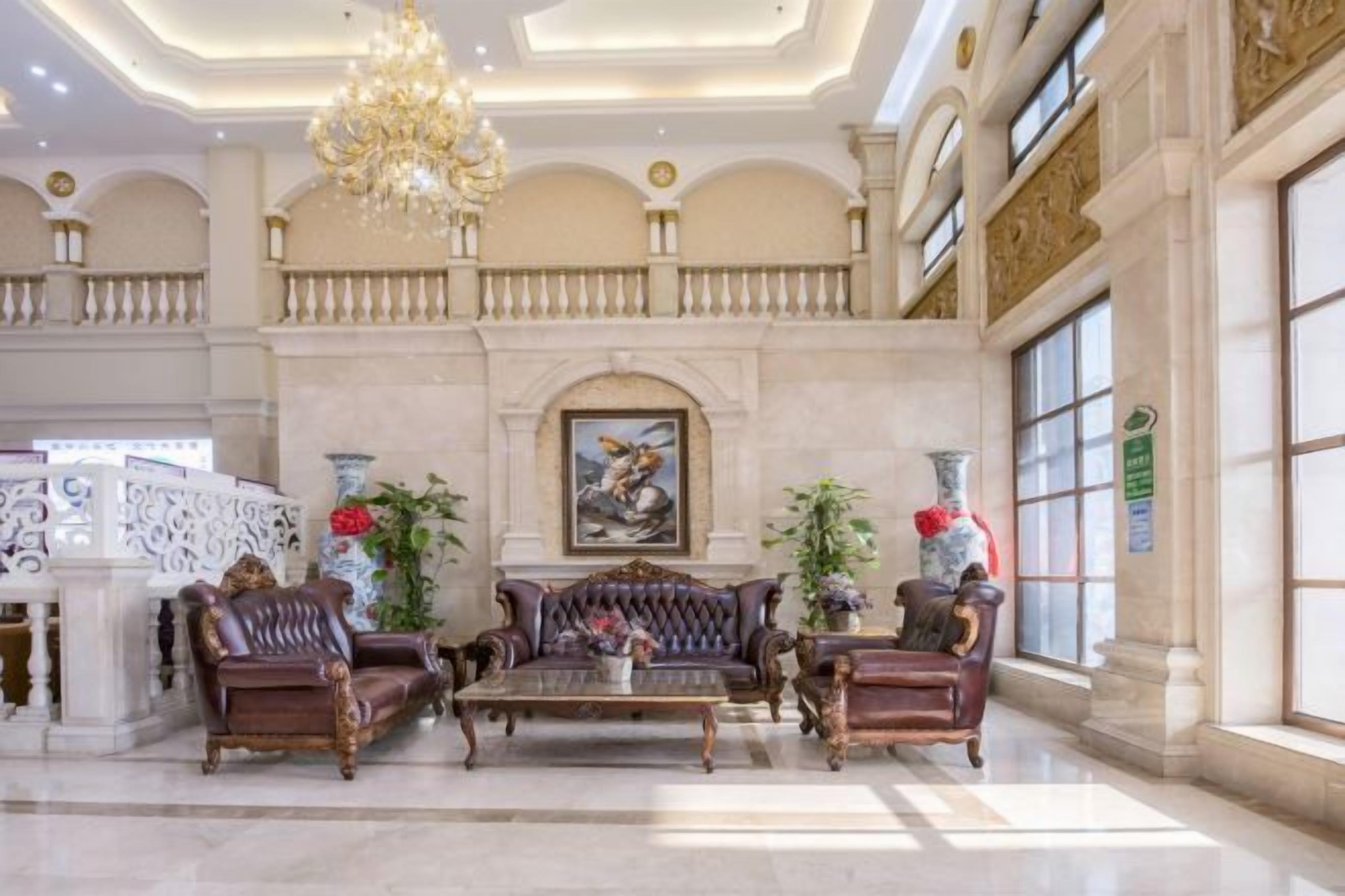 A grand lobby with a chandelier, ornate furniture, and a large painting on the wall.