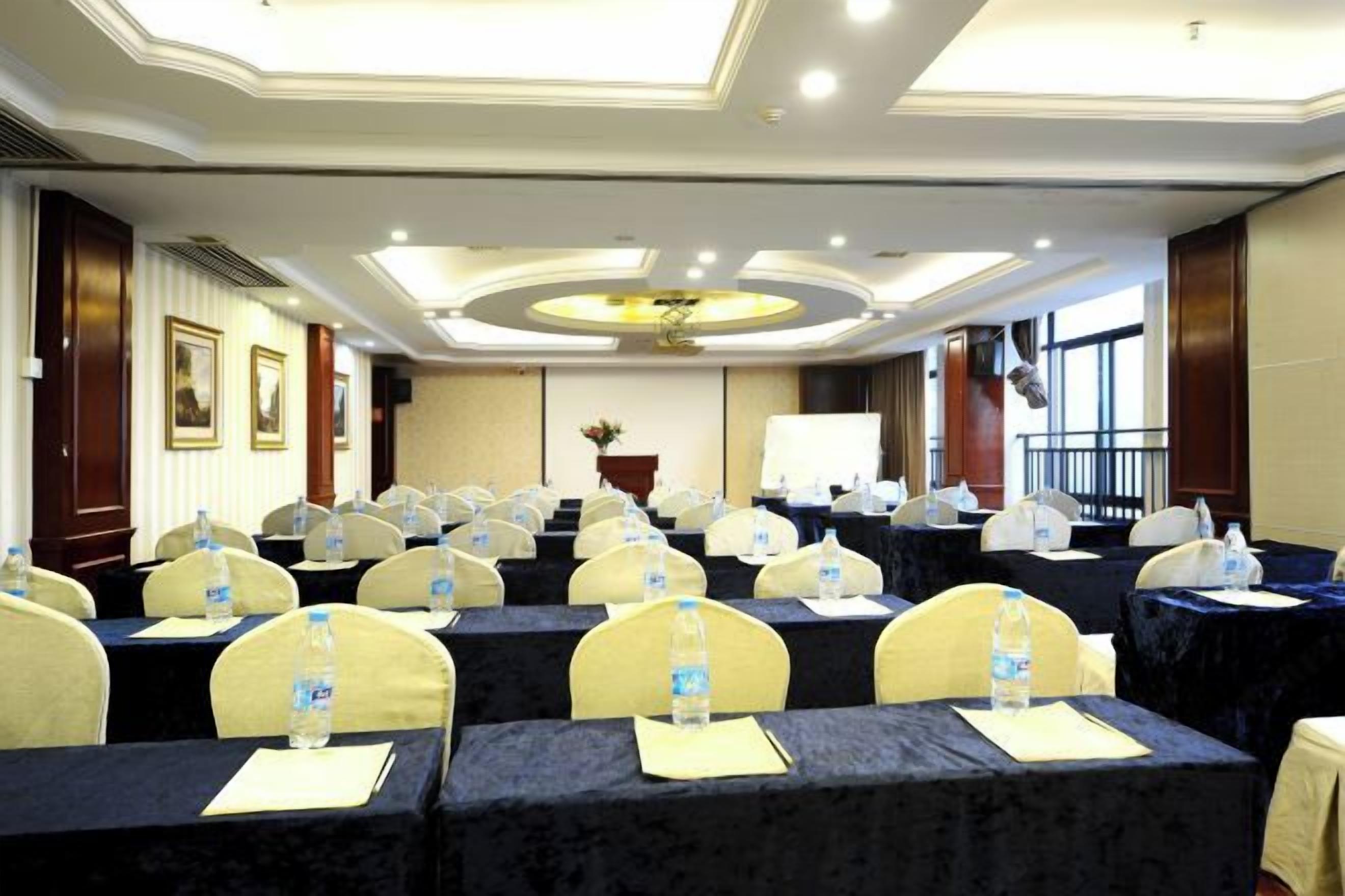 Una sala conferenze con file di tavoli, sedie e bottiglie d'acqua.