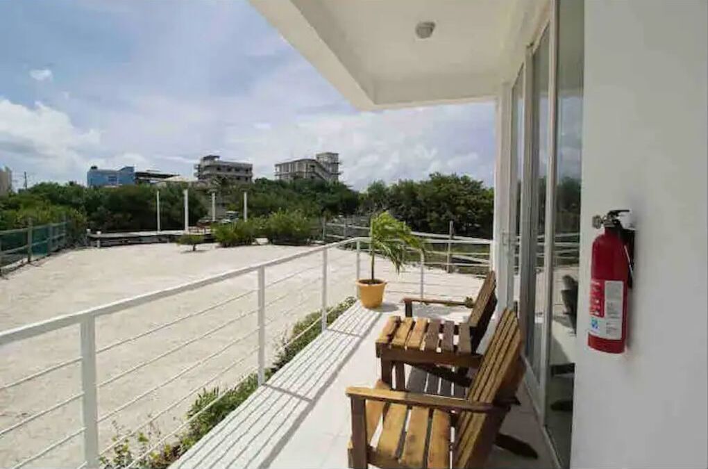 Ein Balkon mit einer Holzbank, einem Blumentopf und einem Feuerlöscher an der Wand.