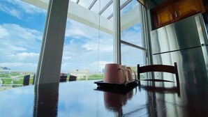 Een eettafel met uitzicht op de lucht en gebouwen door grote ramen.