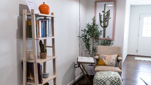 Et værelse med en træbogreol, et lille bord, en stol, en kaktus og en hængende lampe.