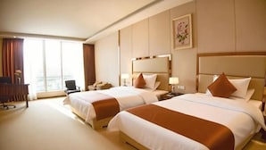 Habitación de hotel con dos camas, un escritorio, una silla y un ventanal grande.