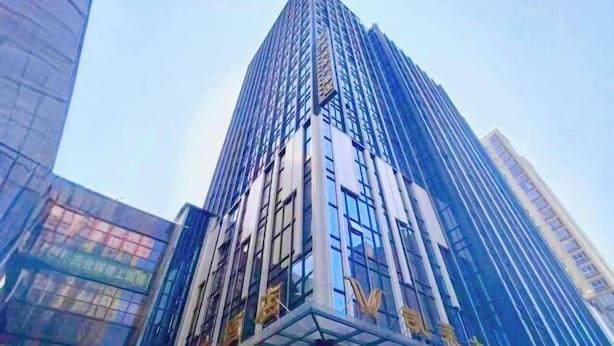 Un edificio alto y moderno con ventanas de vidrio reflectante y un letrero llamativo en la base.
