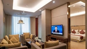 Una habitación de hotel con televisión, sofá, cama y escritorio.