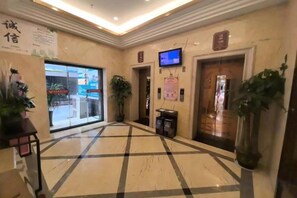 A hotel lobby with a check-in counter, a television screen, and a reception desk. - Kailai Hotel (Yuqing)