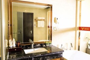 A hotel bathroom with a large mirror, a sink, and a towel rack. - Kailai Hotel (Yuqing)