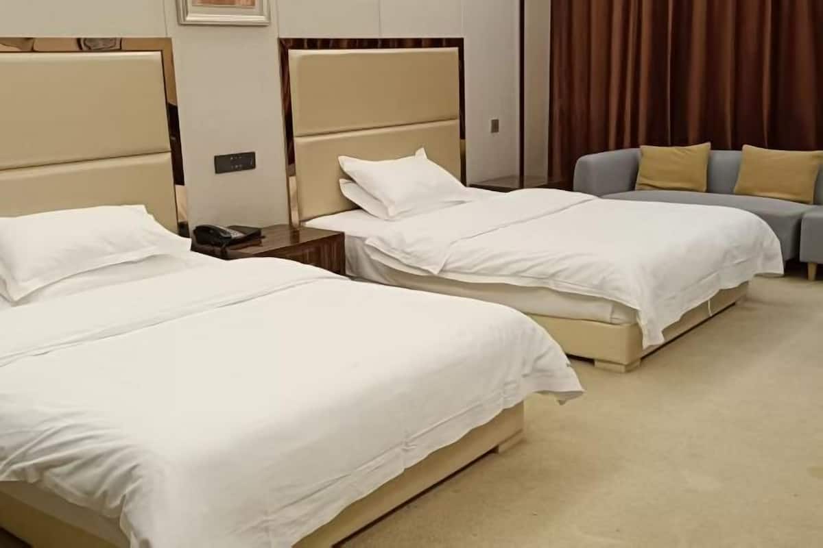 A hotel room with two beds, a sofa, and a curtain.