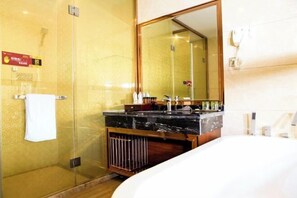 A hotel bathroom with a glass-enclosed shower, a large mirror, a white bathtub, and a vanity with toiletries. - Kailai Hotel (Yuqing)