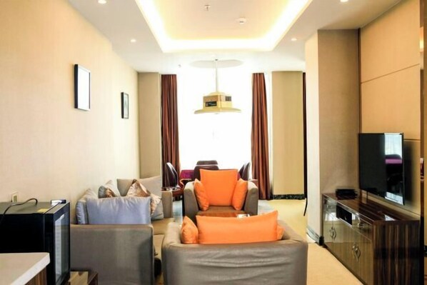 A modern hotel room with a sofa set, a television, and a dining area with a table and chairs. - Kailai Hotel (Yuqing)